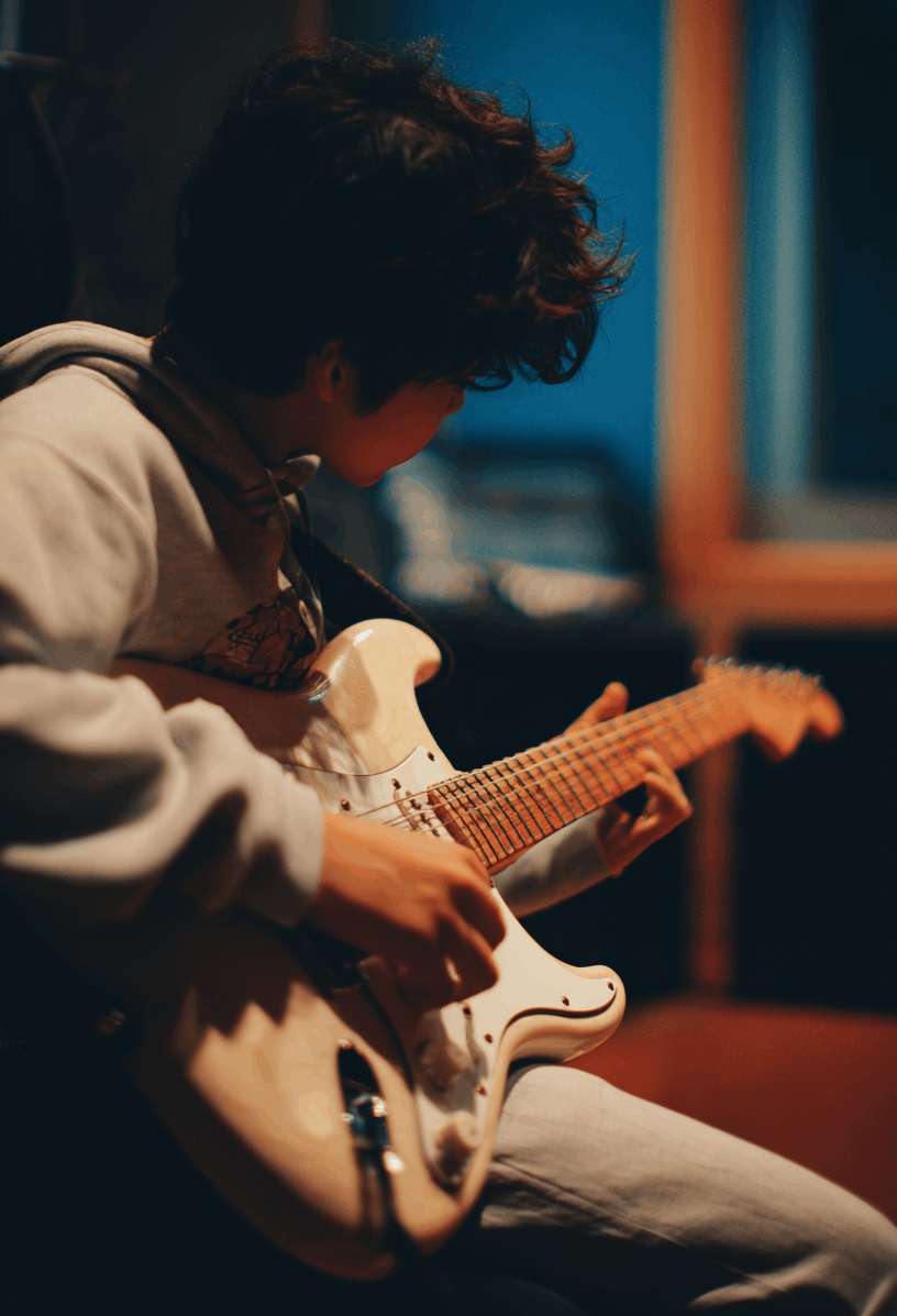 jpeg-optimizer_timmy_budiono_a_medium_shot_of_a_japanese_boy_playing_guitar_fo_9b3abc41-62f7-4ba7-a235-ae859b8d7309-croppad1 En pojke spelar elgitarr.